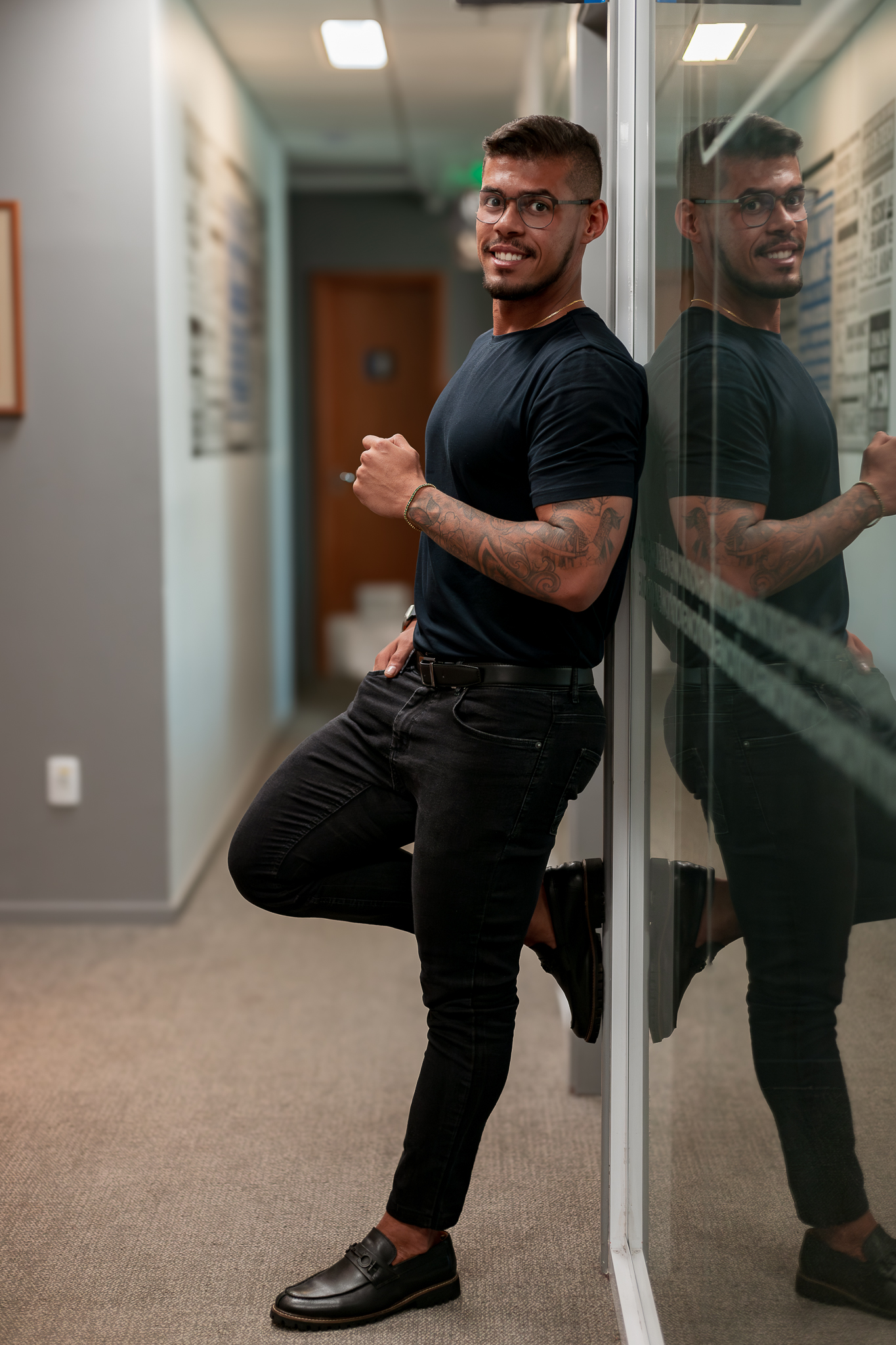 Gabriel Renan em um corredor, ao lado de uma parede de vidro